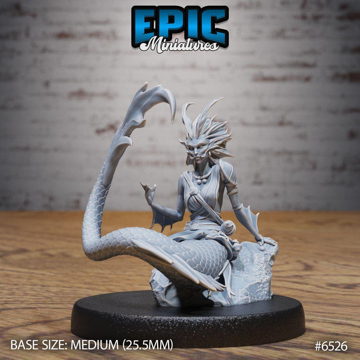 A figurine of a mermaid-like creature with a long tail and a human-like body, sitting on a rock. The figurine is displayed on a black base, and the background is a brick wall.