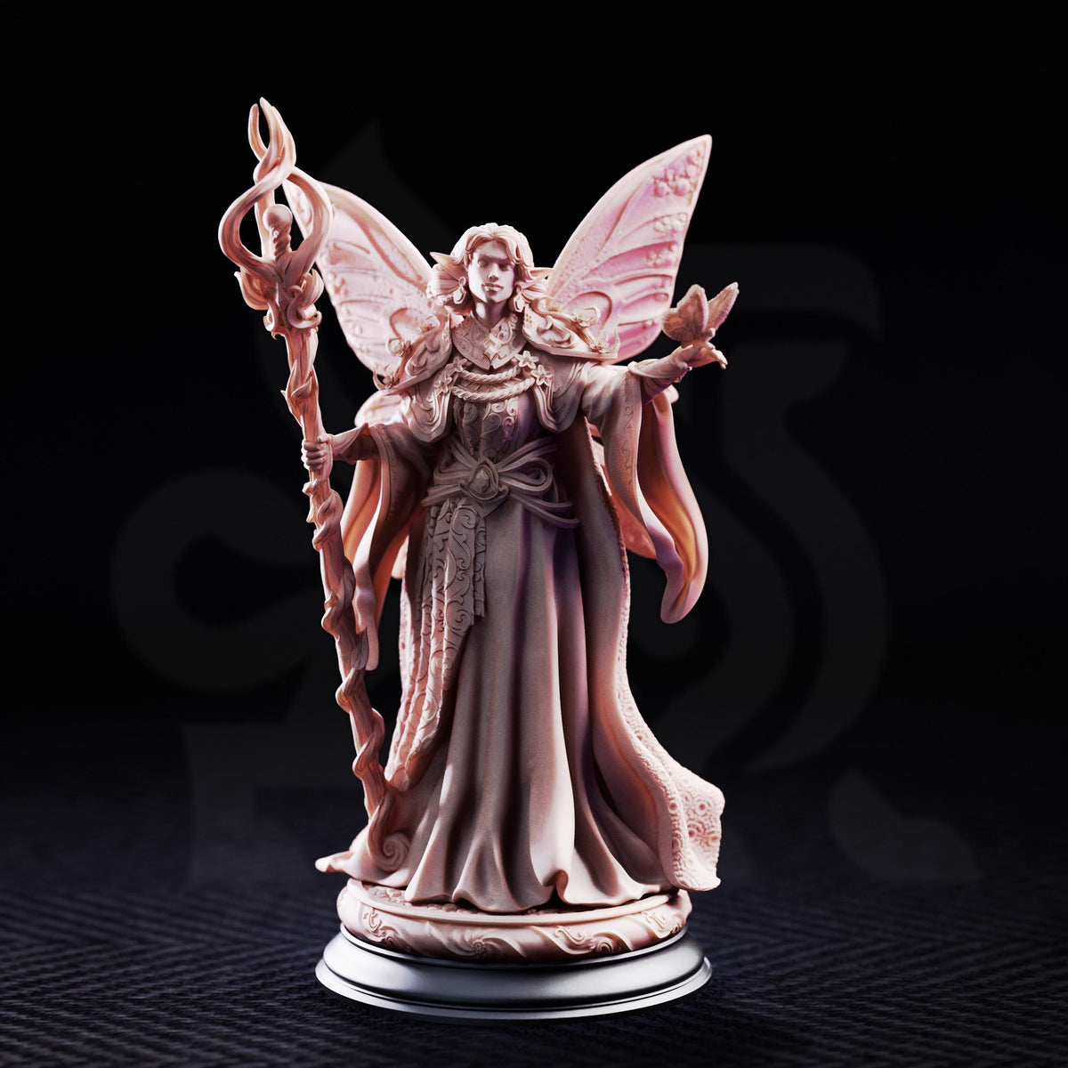 A figurine of a fairy or magical being, with wings and a staff, standing on a pedestal against a dark background.