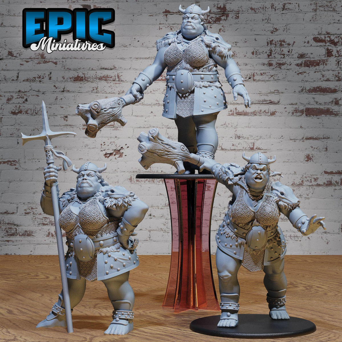 three figurines of women in battle attire, standing on a platform and holding various weapons.