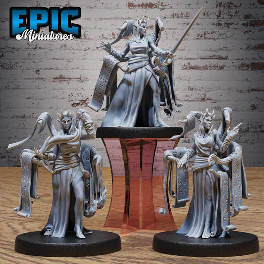 three figurines of female characters, each with unique poses and attire, displayed on a stand against a brick wall background.