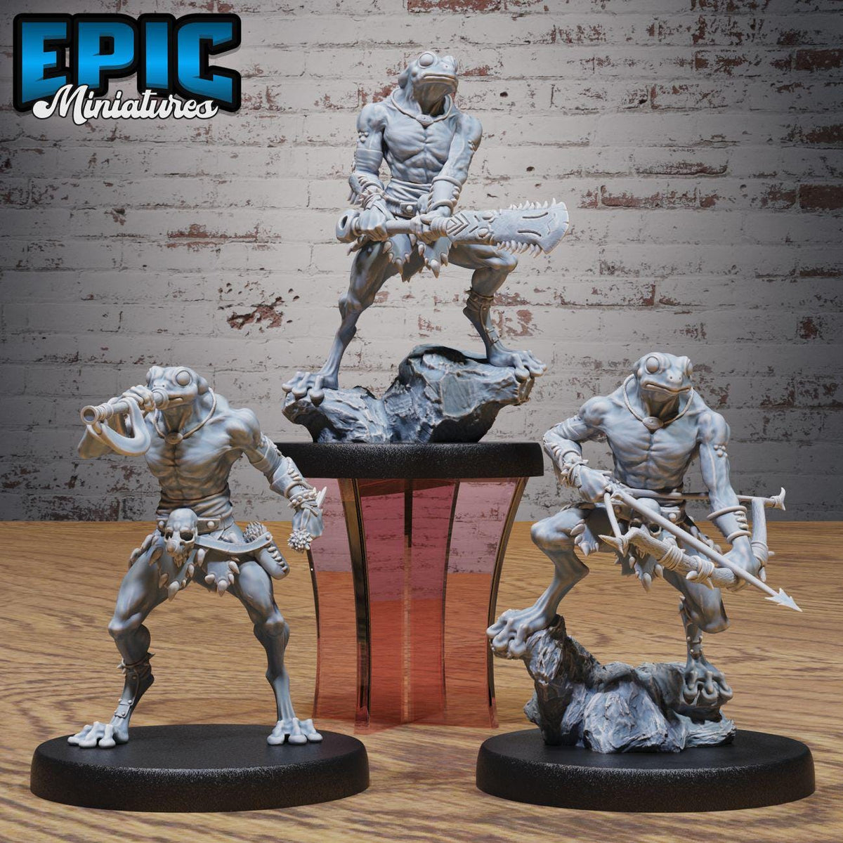three figurines of fantastical creatures, including a dragon-like creature, a human-like creature, and a frog-like creature, each holding various weapons and standing on platforms.
