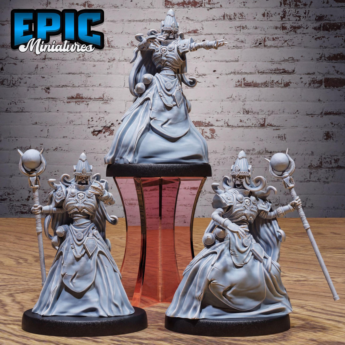 three detailed figurines of characters with ornate, flowing robes and headdresses, standing on a platform against a brick wall background.