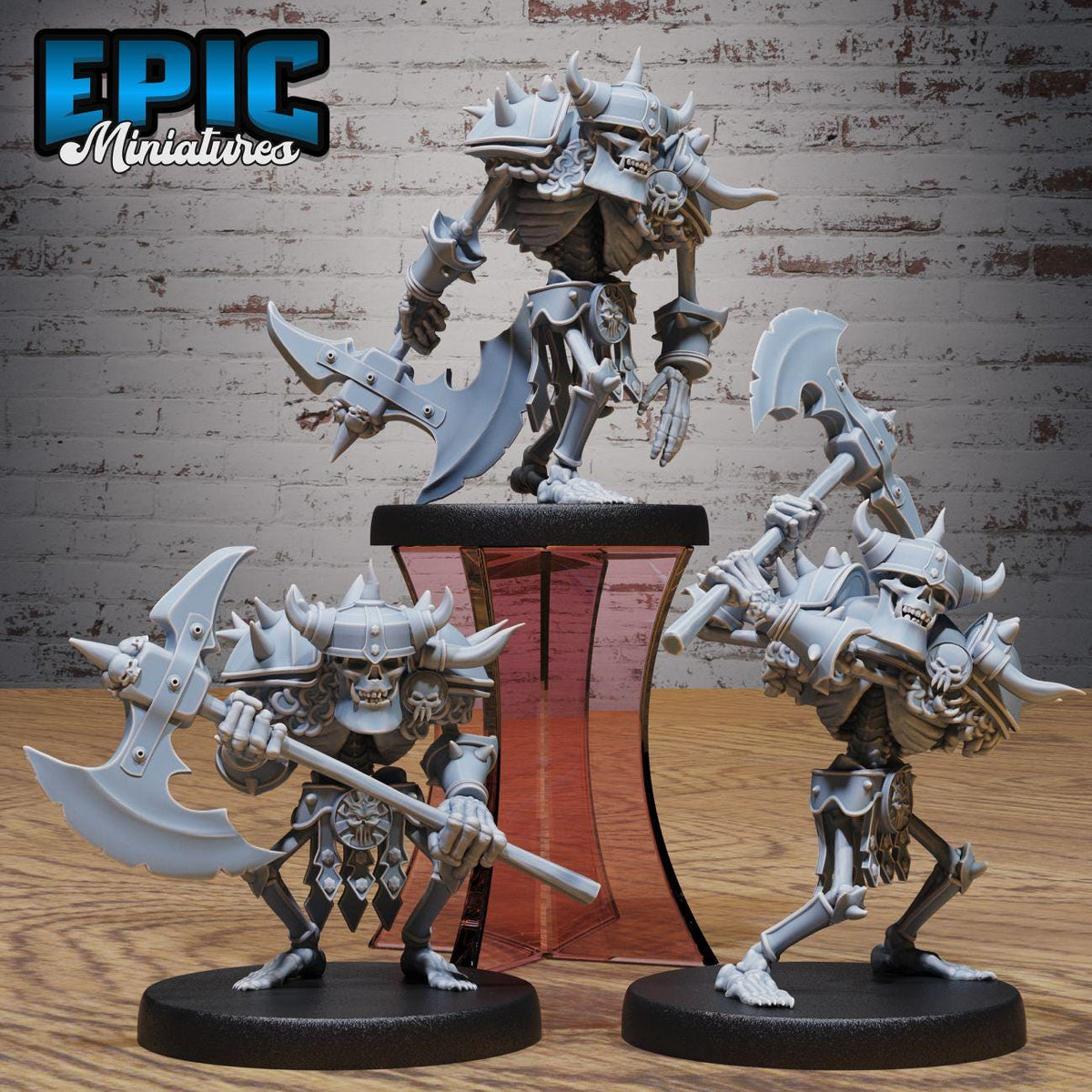 three miniature figures of skeletal creatures, each holding various weapons, displayed on a stand against a brick wall background.