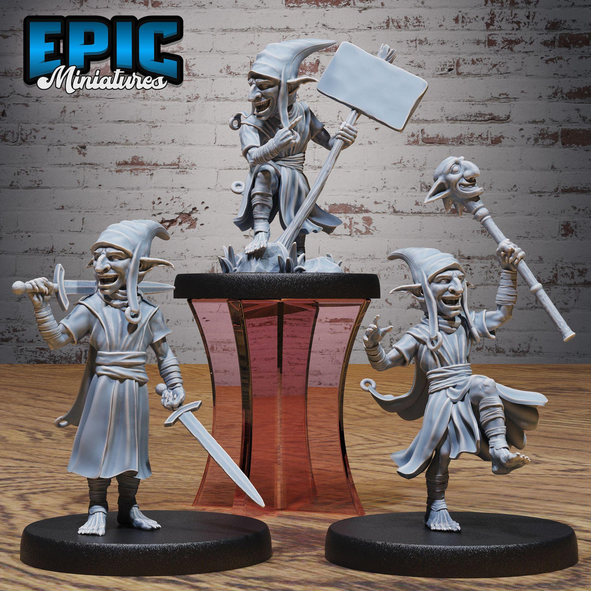 three figurines of fantastical creatures, each holding a unique weapon, displayed on a pedestal against a brick wall background.