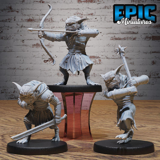 three figurines of fantastical creatures, each holding a weapon and standing on a platform.