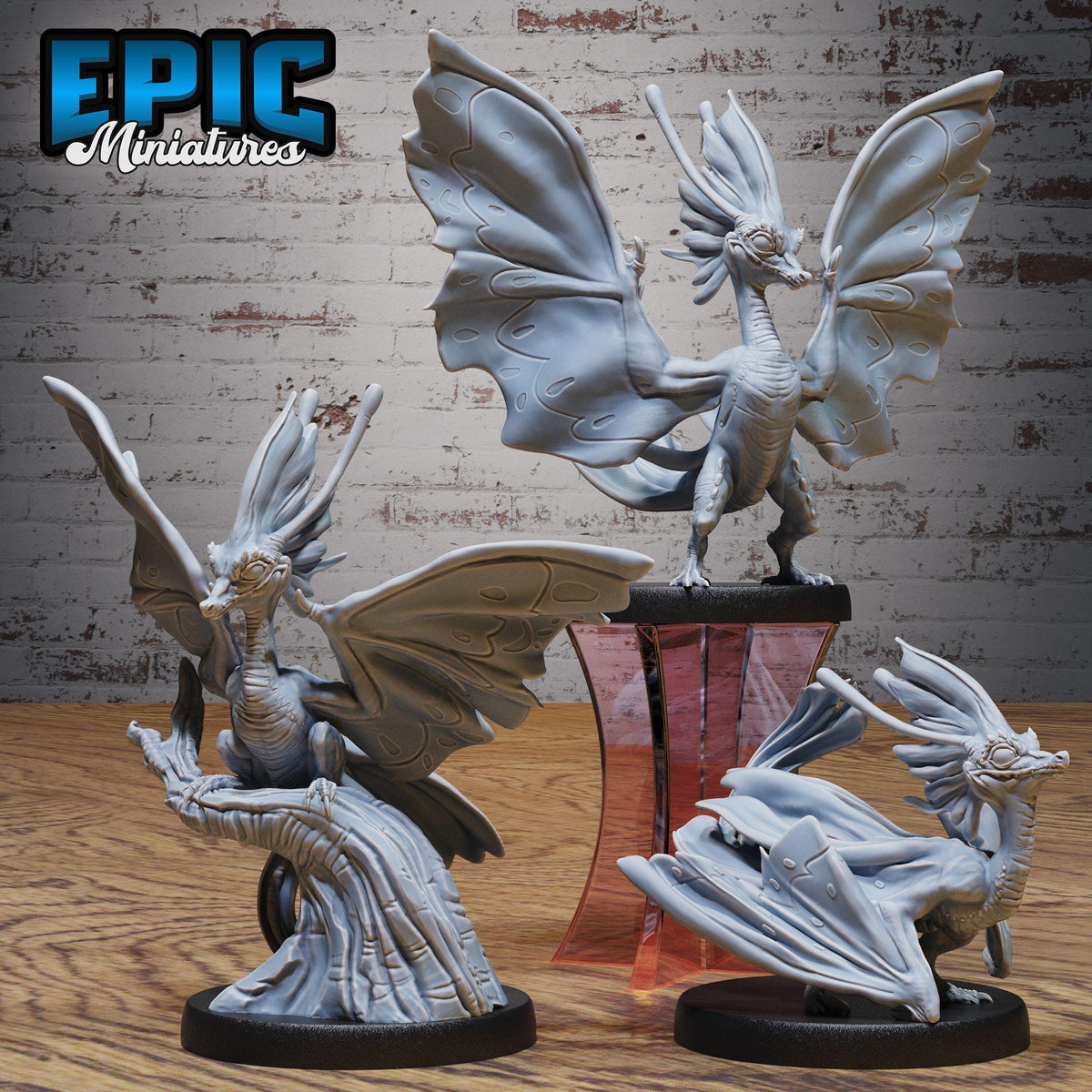 three detailed sculptures of fantastical creatures, including winged, winged, and winged dragon-like figures, set against a brick wall backdrop.