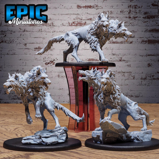 three detailed sculptures of fierce-looking creatures, likely mythical or fantastical, displayed on a wooden surface against a brick wall background.