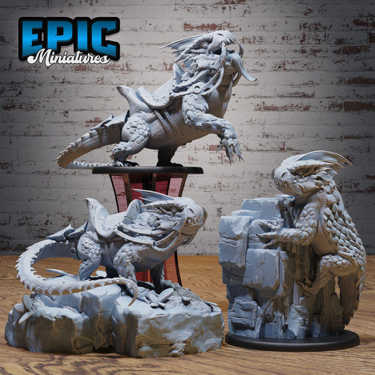 three detailed sculptures of fantastical creatures, including a dragon-like creature, a large, armored animal, and a winged, armored creature, all displayed on a wooden surface against a brick wall background.