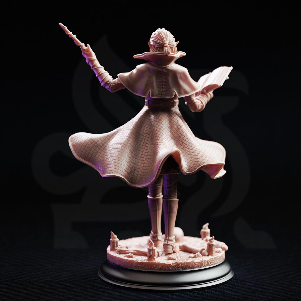 A figurine of a woman with a flowing dress and a crown, holding a book and a staff, standing on a base with candles and other objects.