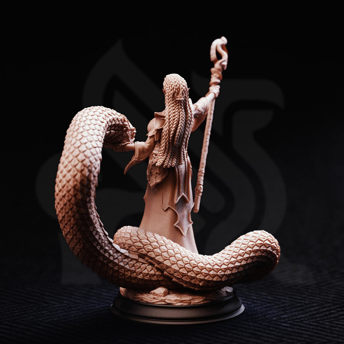 A detailed figurine of a wizard or magical figure, with long hair and a staff, standing on a platform and holding a snake.