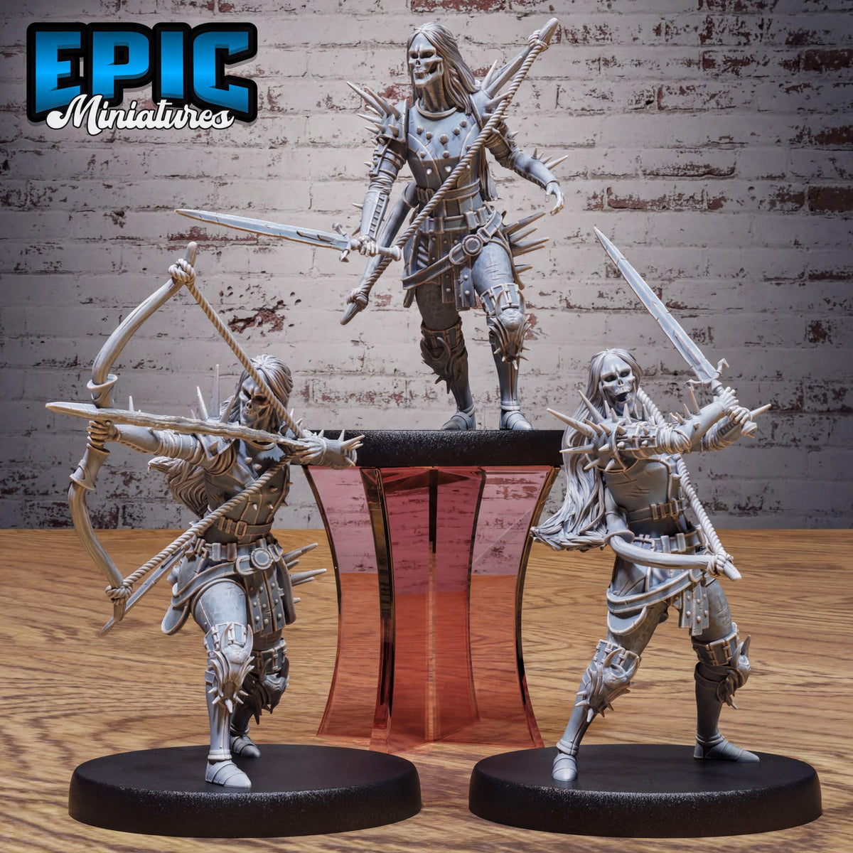 three figurines of medieval-style characters, each holding weapons and standing on platforms.
