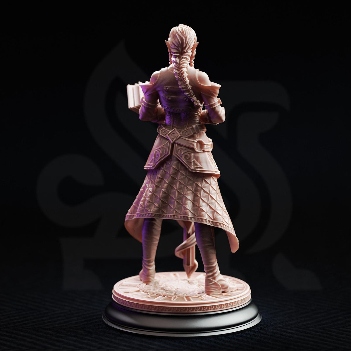 A figurine of a woman with a braided hairstyle and a decorative skirt, standing on a pedestal and holding a book.