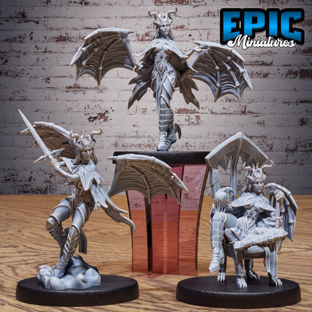 three figurines of winged, winged-winged, winged-winged creatures, possibly representing fantasy creatures or characters, displayed on a wooden surface against a brick wall background.