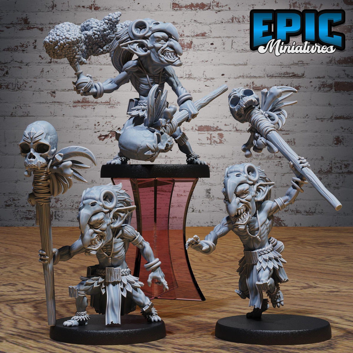 a collection of miniature figurines, including a skull-wielding figure, a winged figure, and a figure with a staff. The figurines are displayed on a wooden surface against a brick wall background.