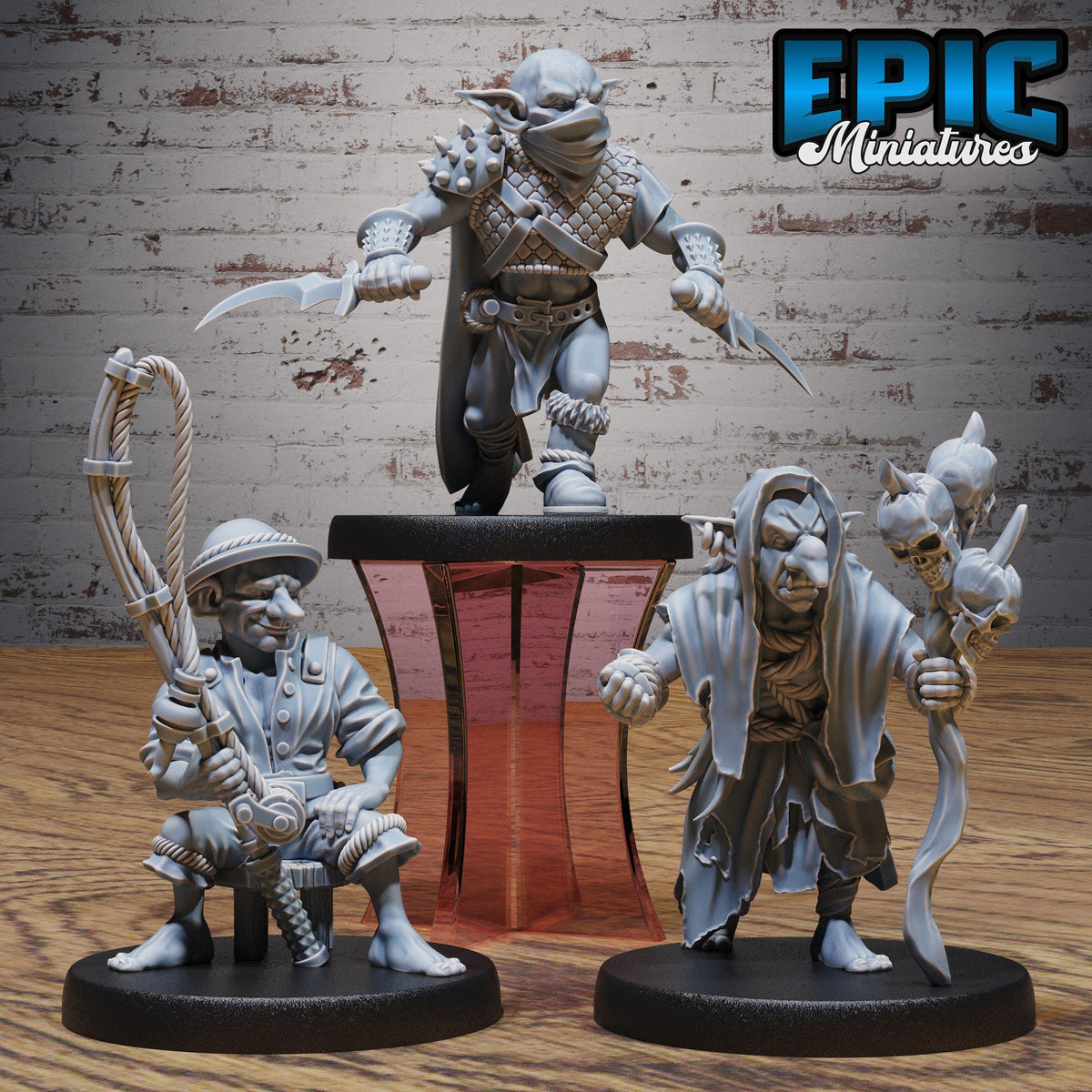 three figurines of characters from a fantasy or science fiction setting, displayed on a wooden surface against a brick wall background.