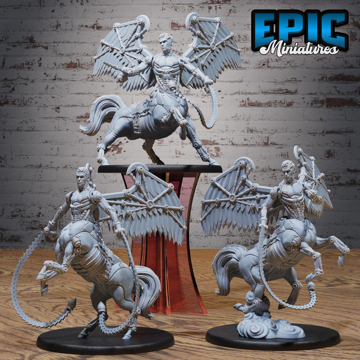 three figurines of winged creatures, possibly mythical or fantastical, displayed on a wooden surface against a brick wall background.