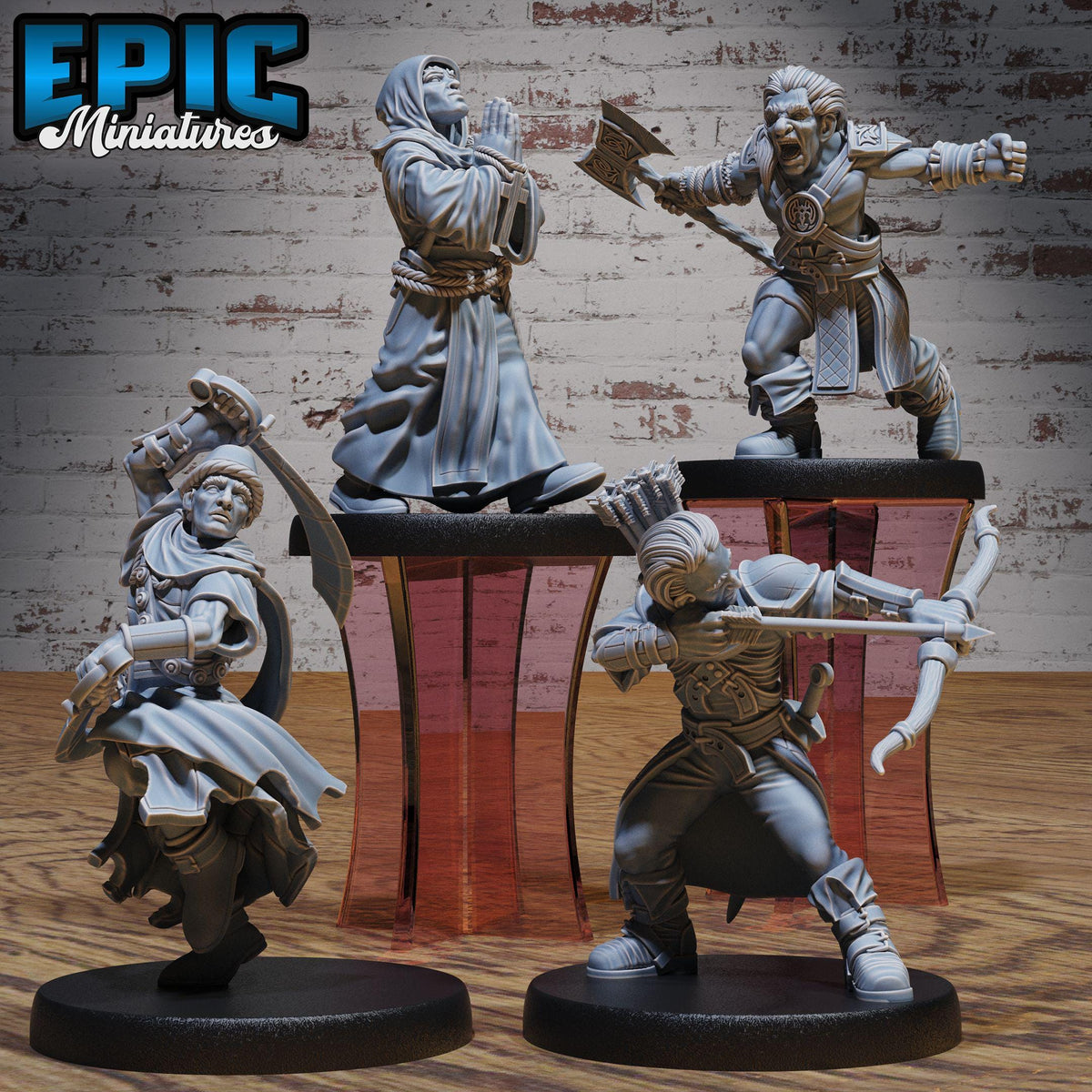 four figurines of characters from a fantasy or adventure game, displayed on a wooden surface against a brick wall background.