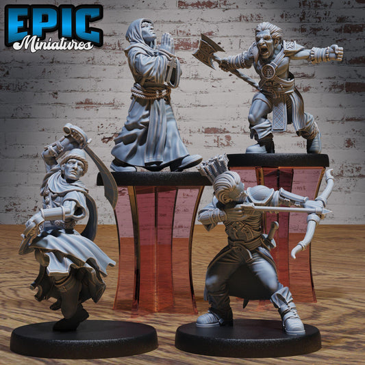 four figurines of characters from a fantasy or adventure game, displayed on a wooden surface against a brick wall background.