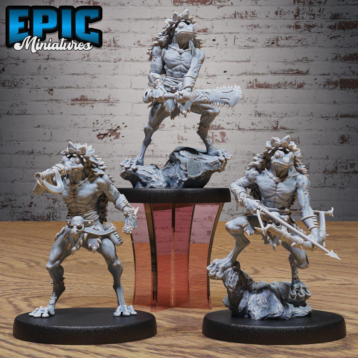 three figurines of fantastical creatures, each holding various weapons, displayed on a wooden surface against a brick wall background.