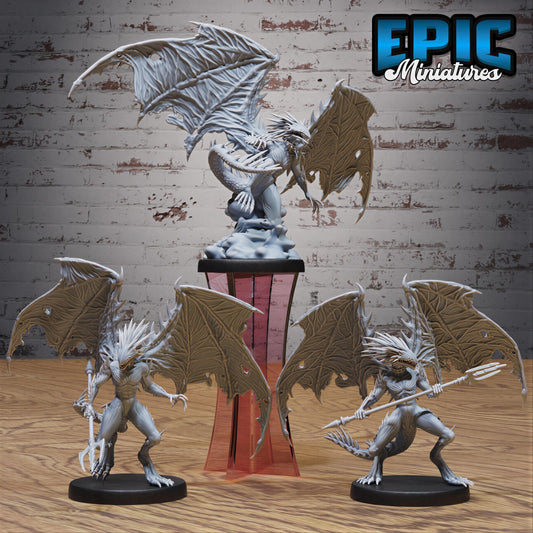 three figurines of winged creatures, possibly mythical or fantasy-inspired, displayed on a wooden surface against a brick wall background.