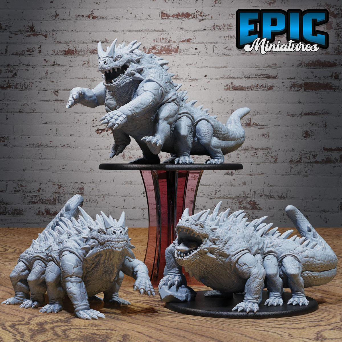 three detailed figurines of fantastical creatures, likely from a fantasy or science fiction setting, displayed on a wooden surface against a brick wall background.
