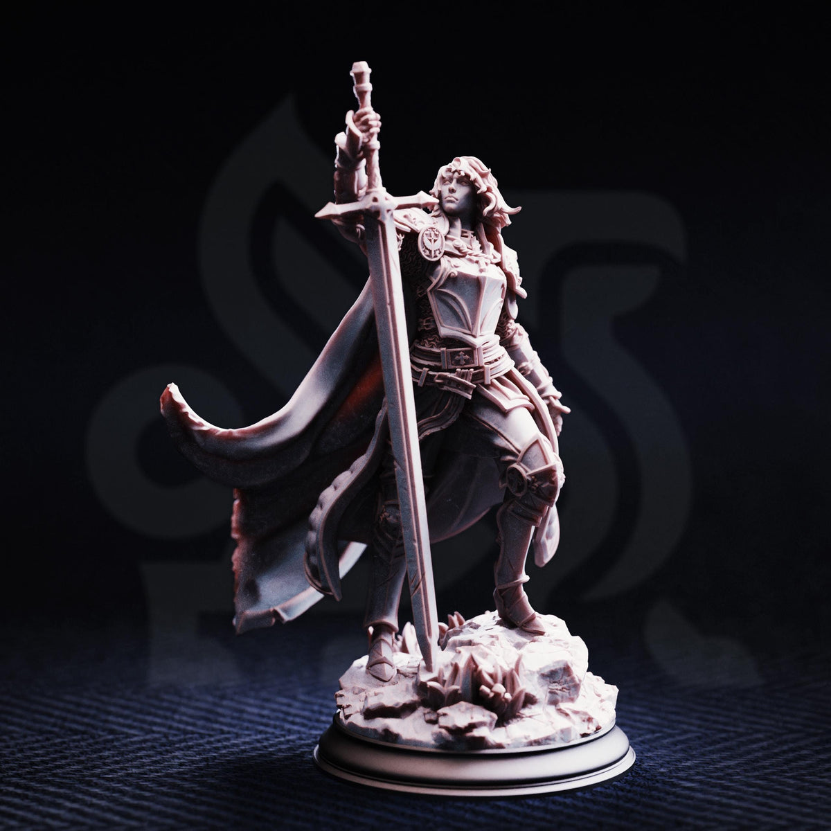 A figurine of a woman holding a sword and standing on a rock formation against a dark background.
