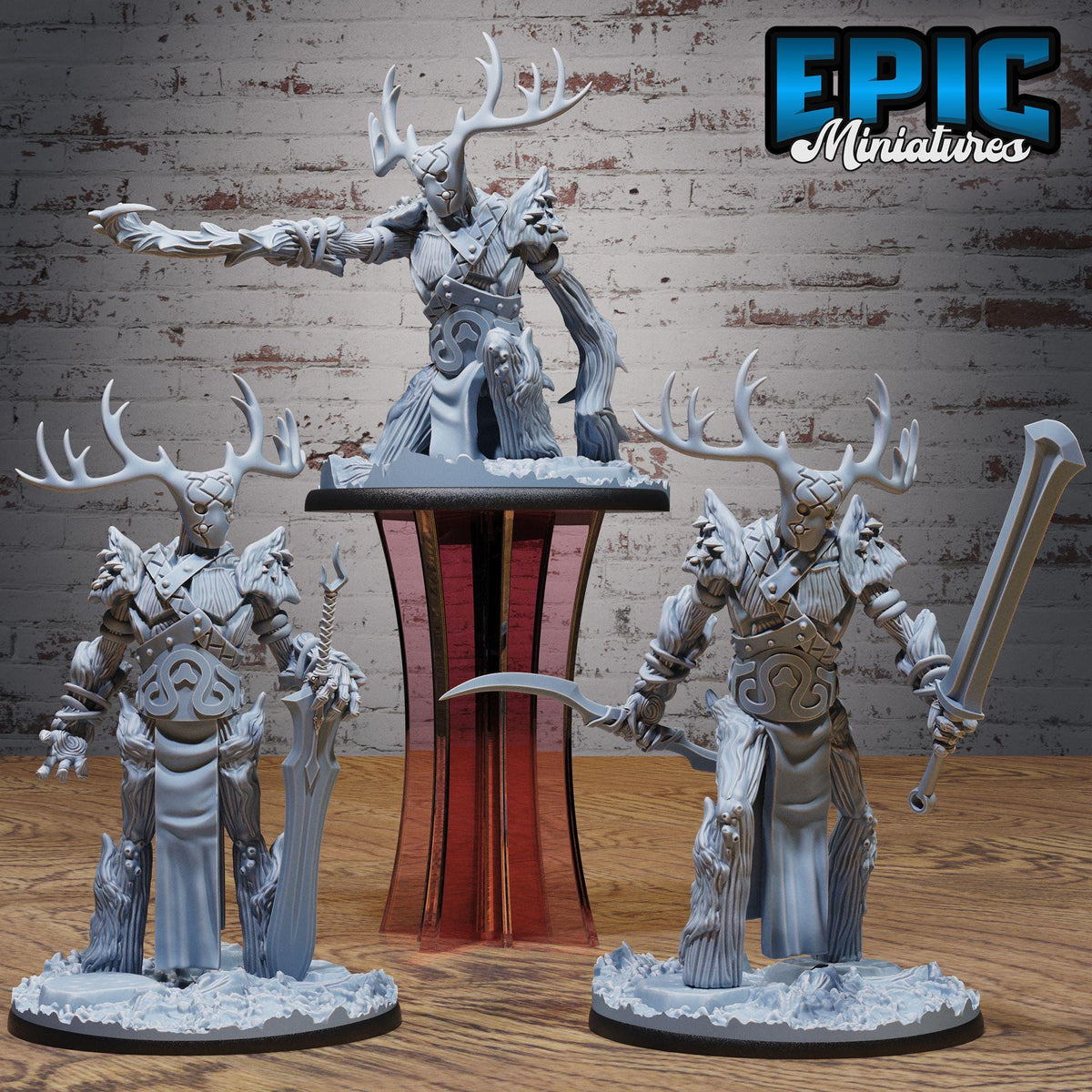 three detailed figurines of fantastical creatures, including a large deer-like creature with antlers, a human-like figure with a sword, and another human-like figure with a spear. The figurines are displayed on a wooden surface, with a brick wall in the background.