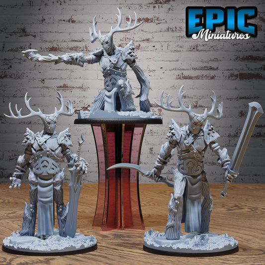 three detailed figurines of fantastical creatures, including a large deer-like creature with antlers, a human-like figure with a sword, and another human-like figure with a spear. The figurines are displayed on a wooden surface, with a brick wall in the background.