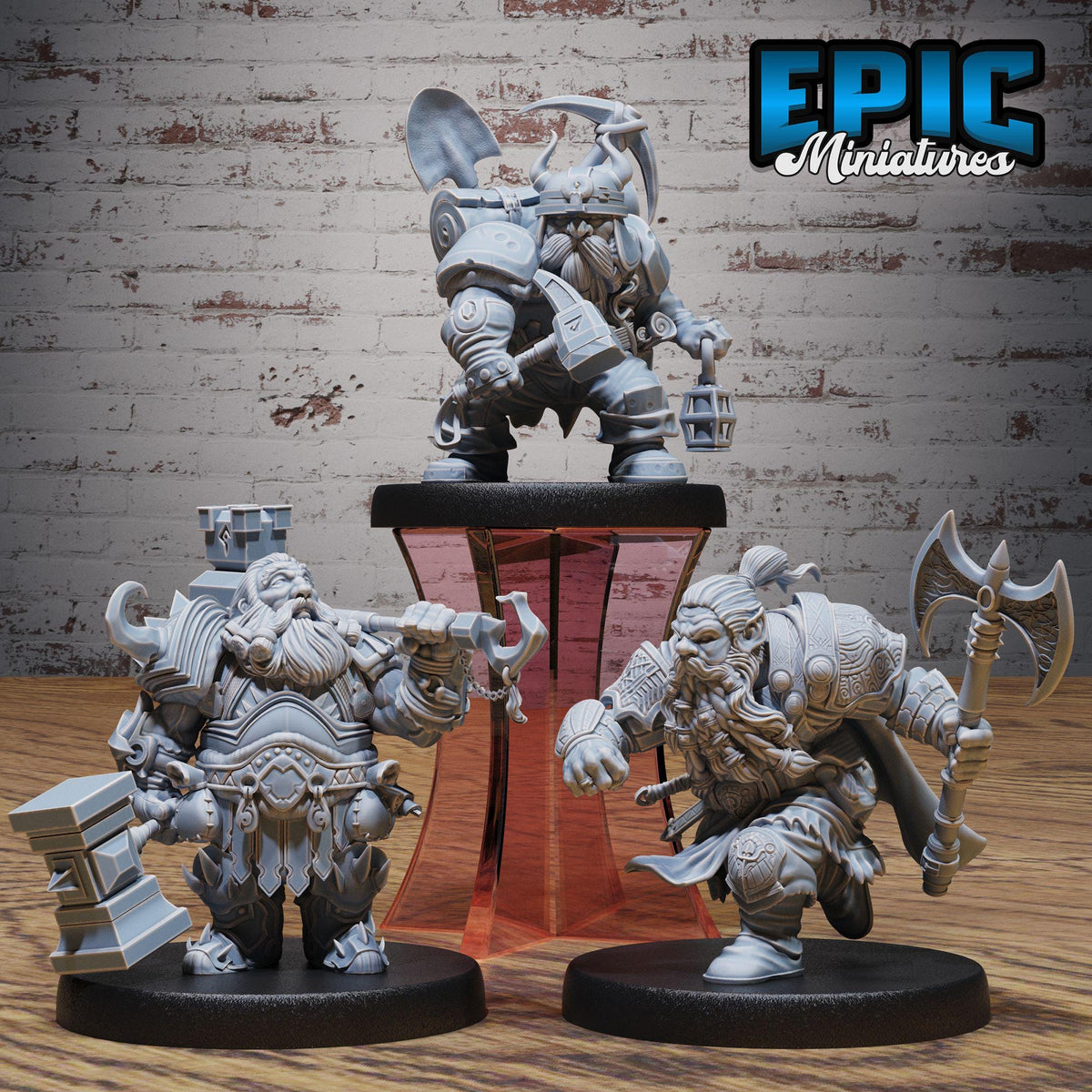 three miniature figurines of dwarfs, each with unique poses and weapons, displayed on a stand against a brick wall background.