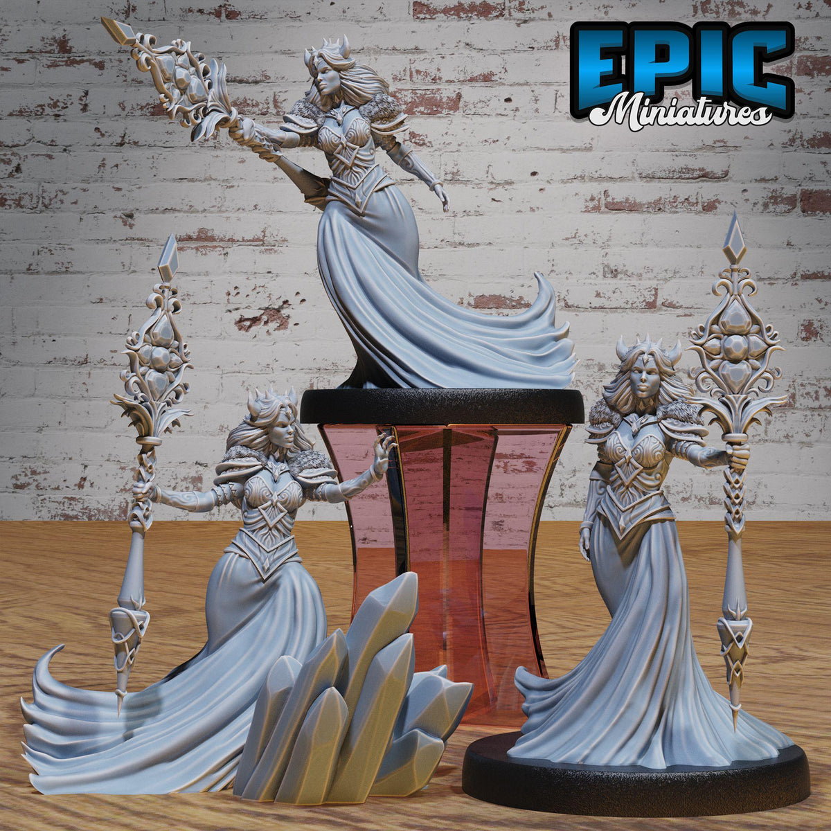 three detailed figurines of women in flowing, ornate dresses, each holding a staff or weapon, set against a rustic brick wall background.