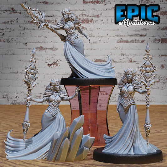 three detailed figurines of women in flowing, ornate dresses, each holding a staff or weapon, set against a rustic brick wall background.