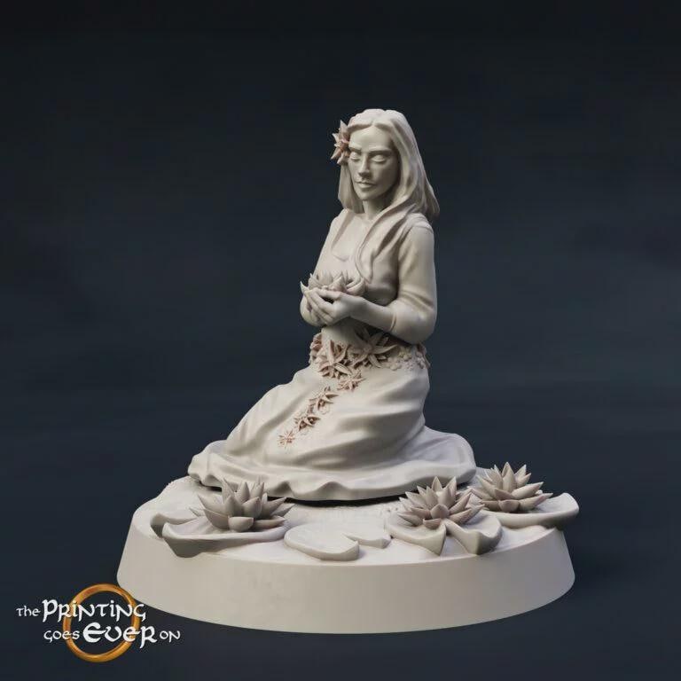A white ceramic figurine of a woman sitting on a rock, holding a flower, with two more flowers nearby.