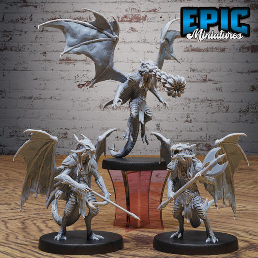 three detailed figurines of winged creatures, possibly dragon or serpent-like figures, posed on a wooden surface against a brick wall background.